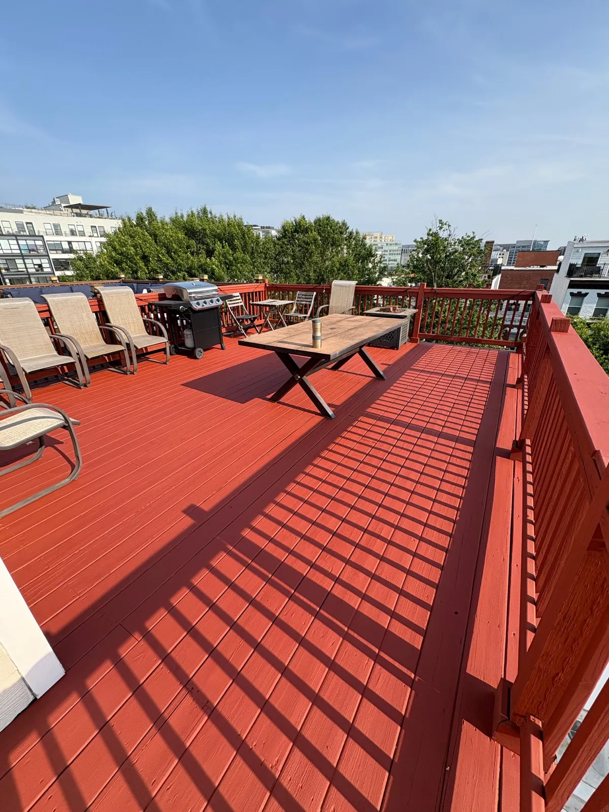 Red-painted rooftop deck with seating and grill