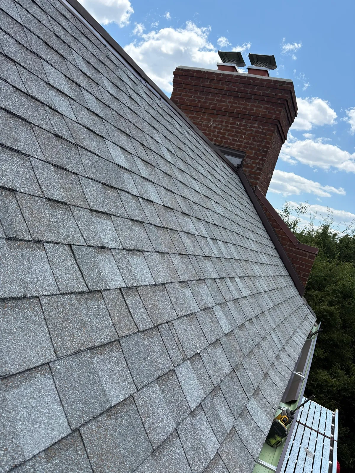 Asphalt shingles meeting brick chimney with flashing
