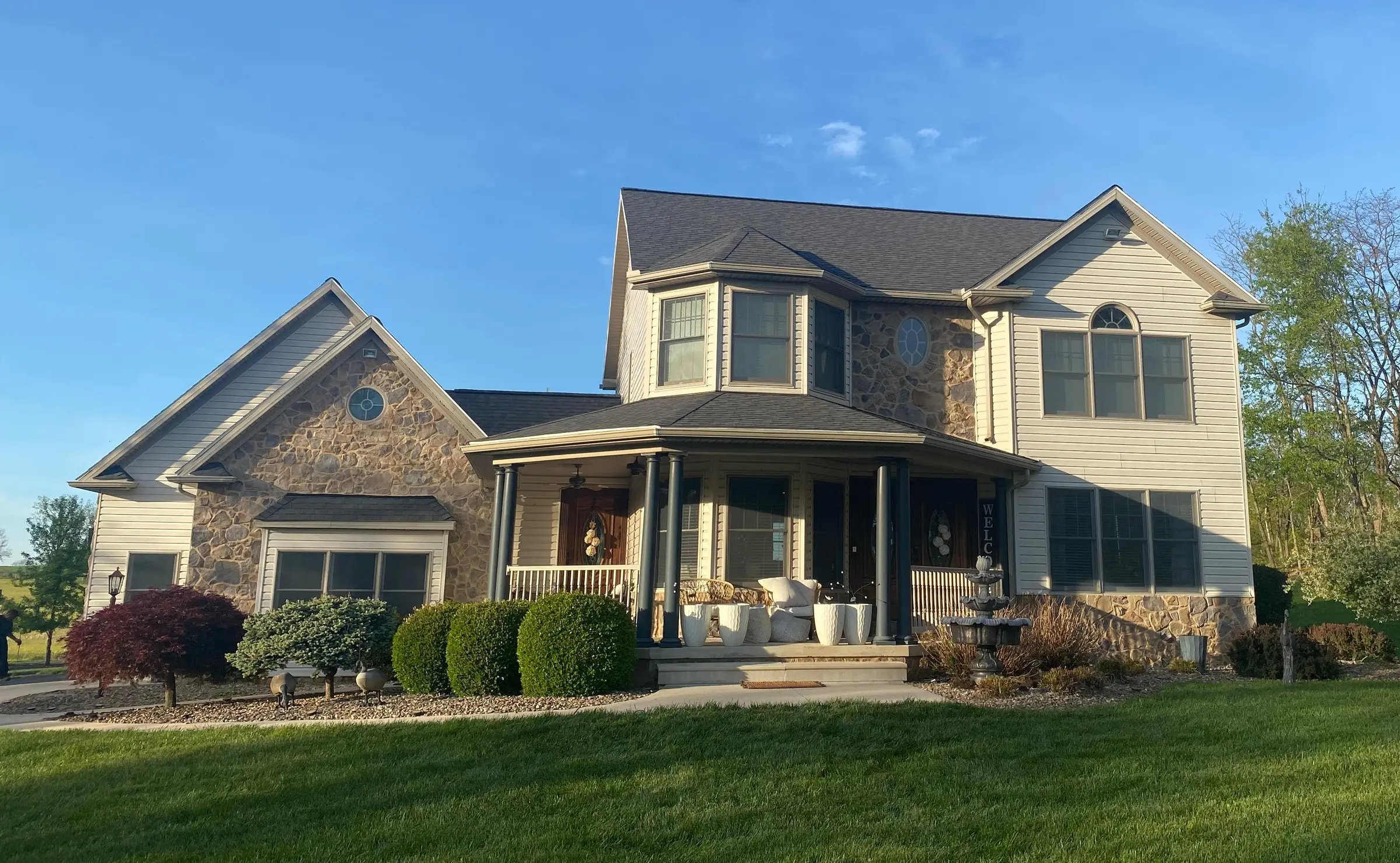 Two-story stone and siding home with a new architectural shingle roof and wraparound porch